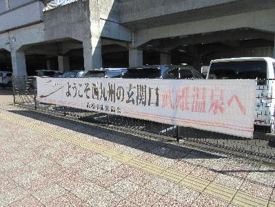 武雄温泉駅の高架下駐車場に設置された文字が薄れた横断幕